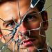 An abstract, high-contrast close-up image of shattered glass reflecting a blurred, distorted face, conveying a sense of damaged reputation and broken trust.