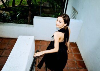 Maude Apatow descending a staircase in a black dress.