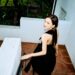 Maude Apatow descending a staircase in a black dress.