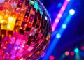 An abstract close-up photograph of shattered disco ball fragments reflecting a colorful array of neon lights, conveying the luxurious, high-energy ambiance of an exclusive celebrity entertainment venue.
