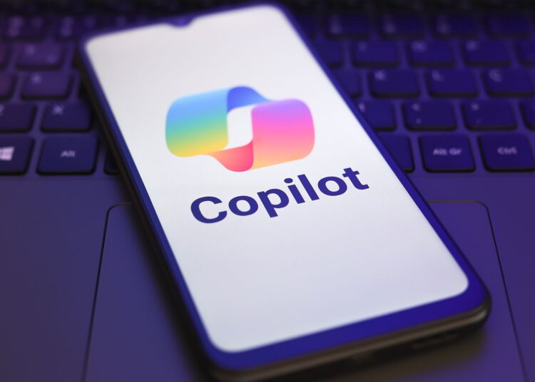Microsoft Copilot logo and branding pictured on a smartphone screen, with smartphone placed on top of a laptop keyboard.