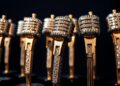 An extreme close-up photograph showcasing the luxurious textures of country music awards and microphones, capturing the high-fashion glamour of the genre's top artists.
