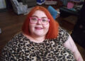 Dolly Martinez smiling, wearing a leopard print shirt and pink glasses.