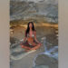 Nicole Scherzinger poses in a zebra bikini while meditating on the beach under a rock formation with her legs crossed.
