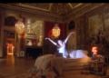 Luxurious room with a bed and a person gesturing dramatically.