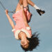 Olivia Rodrigo in a pink dress swings upside down against a blue sky, wearing black shoes and white socks. Parental advisory label in the corner.