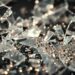 An extreme close-up photograph of shattered glass and glittering sequins, capturing the tension between the film's glamorous aesthetic and the sensitive topic of school shootings.