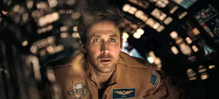 A man in a spacecraft wearing a detailed flight suit looks intensely at a screen, suggesting a scene from a space-themed film or TV show