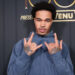 PlaqueBoyMax in a blue hoodie poses with hand gestures in front of a backdrop with logos like VENU, Visa, and Billboard.