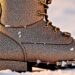 An extreme close-up photograph of a luxurious, glittering ski boot, capturing the high-end, glamorous aesthetic of a private ski resort through dramatic studio lighting and abstract texture.
