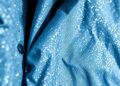 An abstract, high-contrast close-up photograph of a plush, textured ski jacket in muted shades of blue, grey, and white, capturing the luxurious aesthetic of winter sports and the contrasting choices of the royal families.