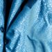 An abstract, high-contrast close-up photograph of a plush, textured ski jacket in muted shades of blue, grey, and white, capturing the luxurious aesthetic of winter sports and the contrasting choices of the royal families.