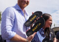 Prince Harry and Meghan laugh and hold black thongs that say 'G'day Hazza' and 'G'day Megs'
