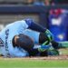 Toronto Blue Jays designated hitter George Springer falls to the ground after taking a foul ball off his foot while playing against the Minnesota Twins during third-inning baseball game action in Toronto, Saturday, April 11, 2026. (Nathan Denette/The Canadian Press via AP)