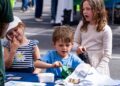 A boy collects his prize after spinning a wheel and answering environmental trivia correctly. He won an environmentally friendly bag for his answer. The activity had rewarded participants while reinforcing sustainability knowledge.