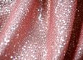 An abstract close-up photograph featuring dramatic, high-contrast lighting on luxurious, glittering fabrics and sequins, conveying the glamorous mood of a Hallmark movie premiere.
