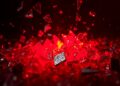 An abstract close-up image featuring shattered glass and metallic fragments reflecting a faint red light, conveying the gritty, industrial energy of Soen's new progressive metal single 'Axis'.