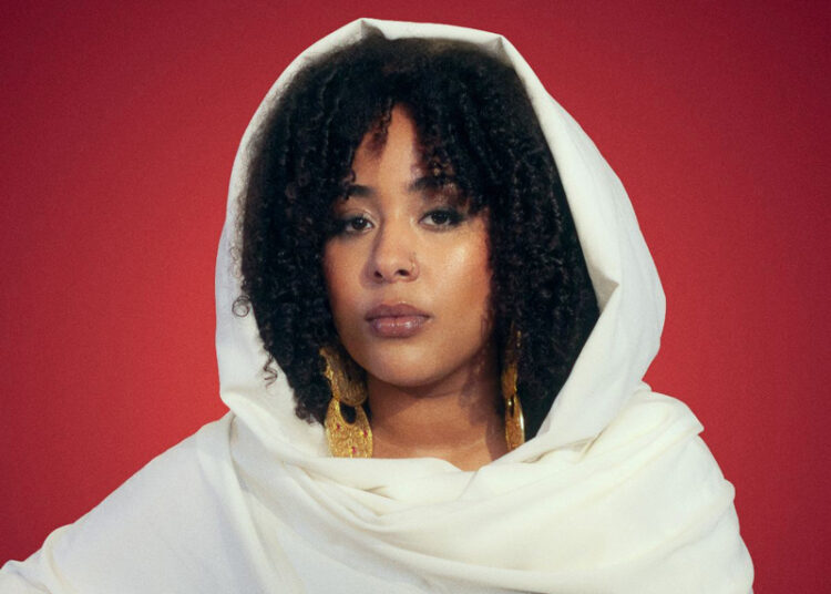 A headshot of Sulaf wearing a traditional white outfit.