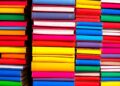 A bold, colorful silkscreen-style illustration featuring a grid of stylized book spines in bright, neon-like hues, conceptually representing the diverse array of literary events and experiences available across Colorado.