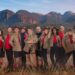 The cast of I'm a Celebrity South Africa 2026 all stood next to each other in brown and red clothing.