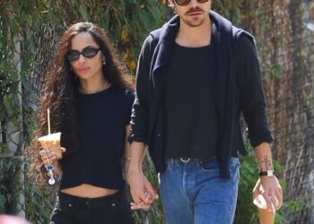 a couple walking handinhand while holding iced coffee drinks