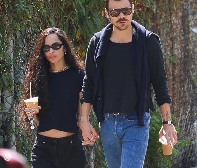a couple walking handinhand while holding iced coffee drinks