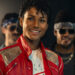 Jaafar Jackson as Michael Jackson smiling in his red jacket in the Michael biopic