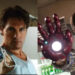 Two men wearing white tank tops imitate the Iron Man pose, each with a glowing mechanical hand extended toward the camera. The left man has brown hair; the right has similar hair and a goatee.