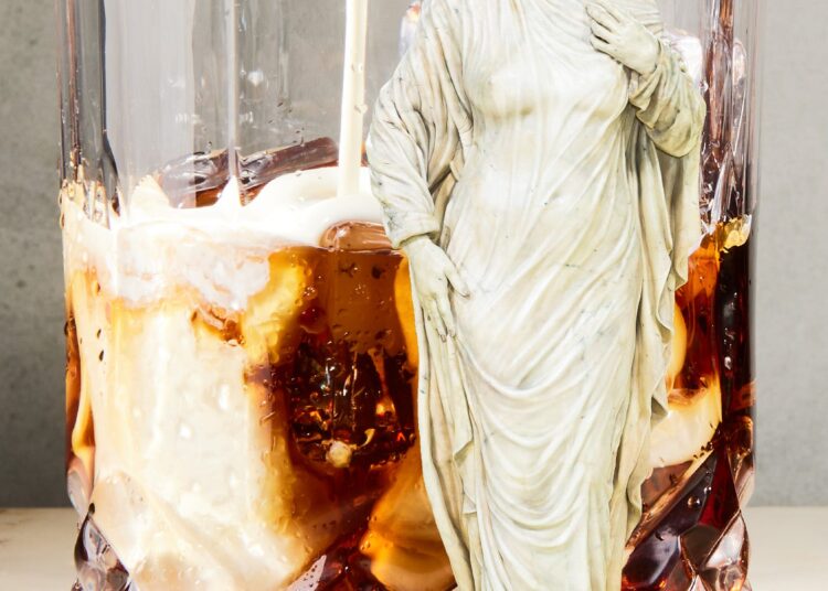 A glass of iced drink with a marble-like figure standing next to it.