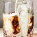 A glass of iced drink with a marble-like figure standing next to it.