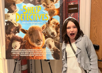 A child looking excited in front of a sheep detectives poster.