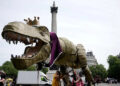 People take part in a march organised by the anti-monarchy pressure group Republic, accompanied by a fifteen-foot dinosaur mascot named Chuck the Rex, from Trafalgar Square to Buckingham Palace (PA)