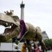 People take part in a march organised by the anti-monarchy pressure group Republic, accompanied by a fifteen-foot dinosaur mascot named Chuck the Rex, from Trafalgar Square to Buckingham Palace (PA)