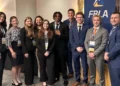Group of conference attendees in business attire posing beside a FRLA banner.