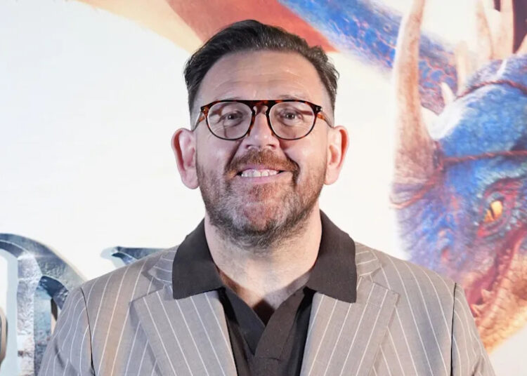 Nick Frost wearing a brown suit and brown-framed glasses.