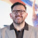 Nick Frost wearing a brown suit and brown-framed glasses.