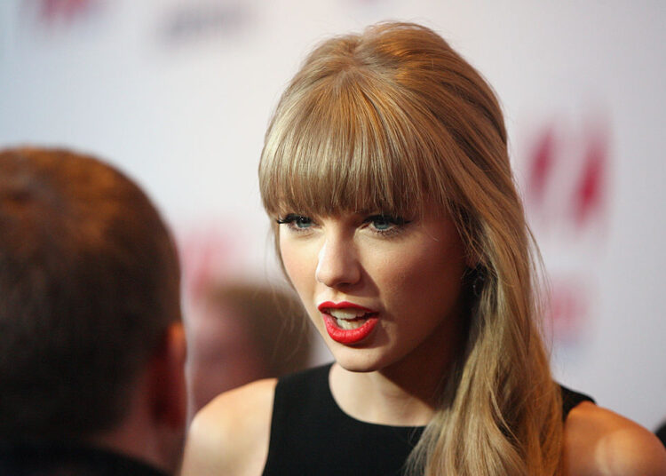 Taylor Swift speaking to a man with his back to the camera.