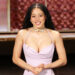 Chase Ifiniti in a light purple dress with long braided hair smiles on stage, wearing a choker necklace.