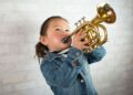 Young girl wearing a demin jacket playing the trumpet (child, musical instruments, Asian ethnicity)
