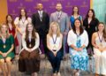 Group of award recipients wearing medals pose for a photo in front of a University of Scranton backdrop.