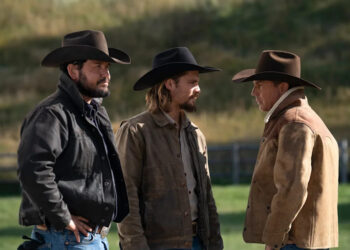 Cole Hauser, Luke Grimes and Kevin Costner in "Yellowstone." Three men in cowboy hats stand outside on a ranch.