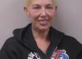 Mugshot of Kim Mathers, Eminem's ex-wife, smiling while wearing a black hoodie.