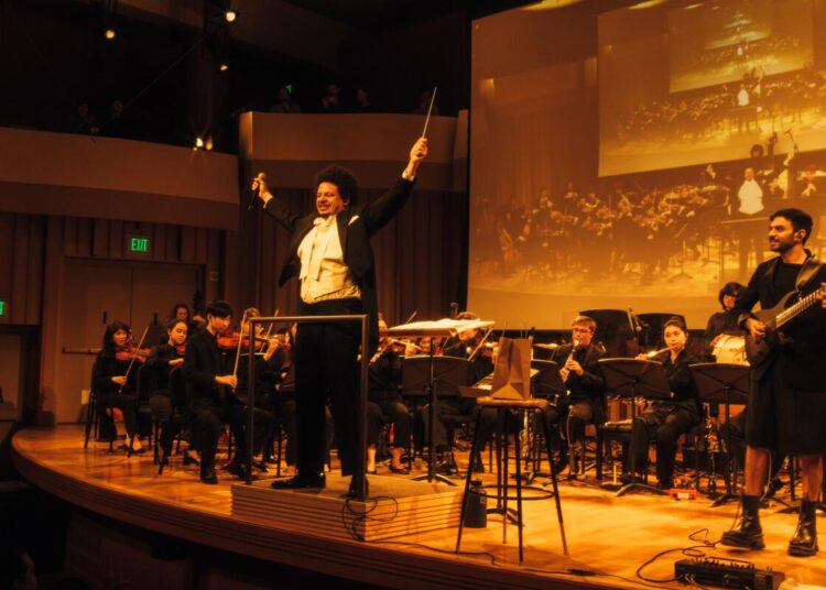 Eric André conducting on stage alongside Prateek Rajagopal, who collaborated with him on his debut classical album.