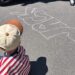 Child sitting on pavement with chalk drawing.