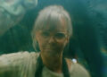Sally Field looking through glass that she is cleaning in Remarkably Bright Creatures.
