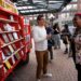 A man talks to people looking at mobile shelves filled with books.