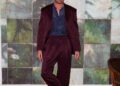 man in a stylish outfit standing against a textured backdrop