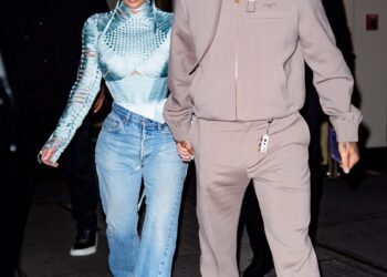 Two individuals holding hands, walking together at night.