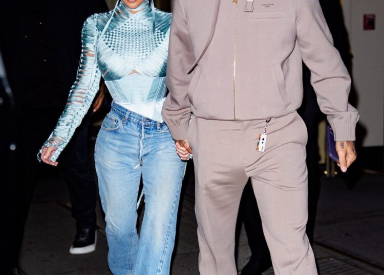 Two individuals holding hands, walking together at night.