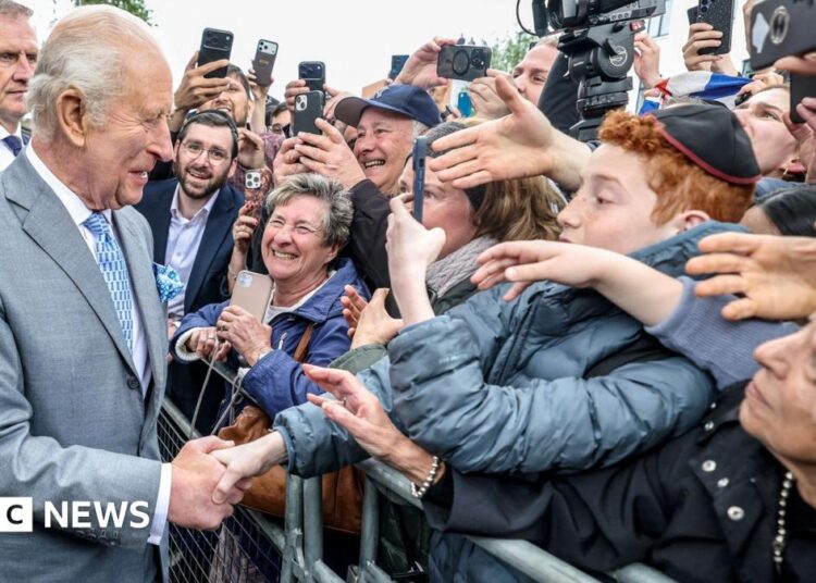King Charles III is presented with flowers as he leaves the Jewish Care building during his visit to Golders Green